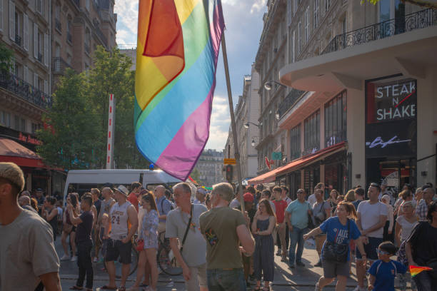 Paris, France - June 30, 2018: A crowd is looking at a float coming there way with a rainbow flag in the foreground, taken during the 2018 gay pride.