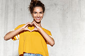 Happy young woman showing heart with hands.