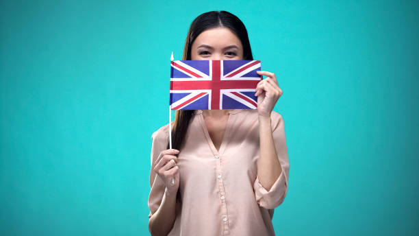 istock Girl covering face with British flag, learning language, education and travel 1169983396