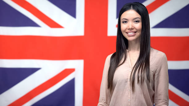 istock Pretty lady standing against British flag background, international cooperation 1169983670