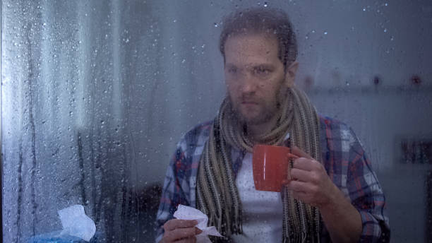 istock Unhealthy man suffering cold, holding handkerchief and beverage cup, bronchitis 1169984598