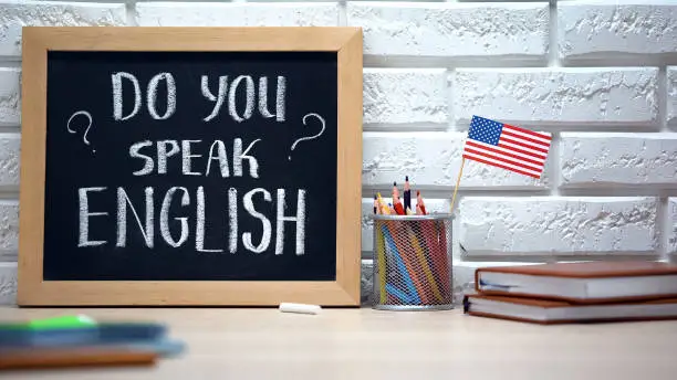 Photo of Do you speak English written on board, international flag in box, language