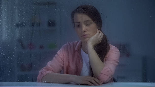 istock Pensive woman thinking about life problems, sitting behind rainy window, trouble 1169984851
