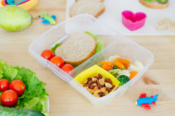 istock Plastic lunch box with sandwich, boiled mixed vegetables, tomato and snack 1169985483