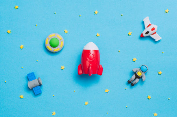 Spaceship, rocket, astronaut, UFO toys on blue background with blank space for text. Top view, flat lay.
