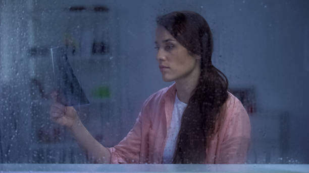 istock Death sick lady looking on lungs x-ray behind rainy window, no hope for recovery 1169985666