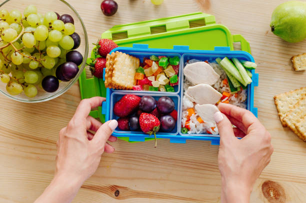 primer plano de manos femeninas preparando carne para la lonchera llena de arroz, verduras frescas, bayas y merienda - bento fotografías e imágenes de stock