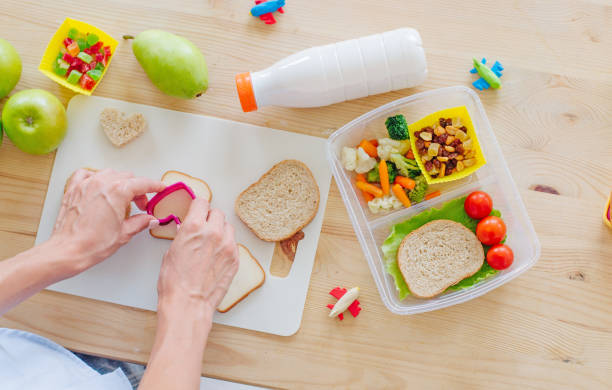 弁当箱にサンドイッチを用意する女性の手のクローズアップ - vegetable fruit cutting board plank ストックフォトと画像