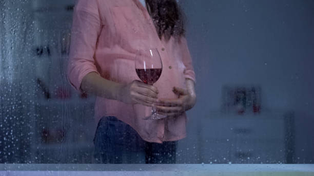 donna incinta accarezza la pancia e beve vino il giorno della pioggia, bambino indesiderato - abdomen addiction adult alcohol foto e immagini stock