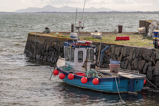 Inshore fishing boat moored at a stone pier at Kircubbin, County Down (Northern Ireland).  In the distance is Strangford Lough and the outline of the Mourne Mountains.