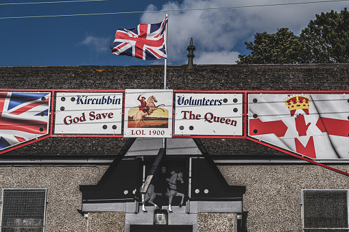 Kircubbin, United Kingdom - August 17, 2019: A British flag flying from an Orange Hall, decorated for July 12th with a banner to mark July 12th.  July 12th (called 'The Twelfth') is a public holiday in Northern Ireland on which members of the Orange Lodge celebrate their British identity and the Battle of the Boyne (1690).  Kircubbin, County Down, Northern Ireland.