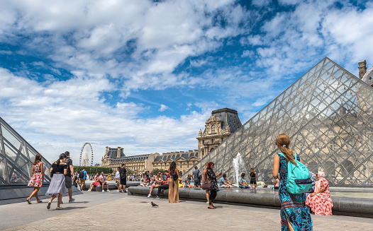 Paris, France - August 4, 2019: The central entrance courtyard to the Louvre Museum surrounded in summer by an overwhelming crowd of tourists in Paris, France. Opened at the end of the 18th century, the Louvre Museum is the most important museum in France and one of the most visited in the world.