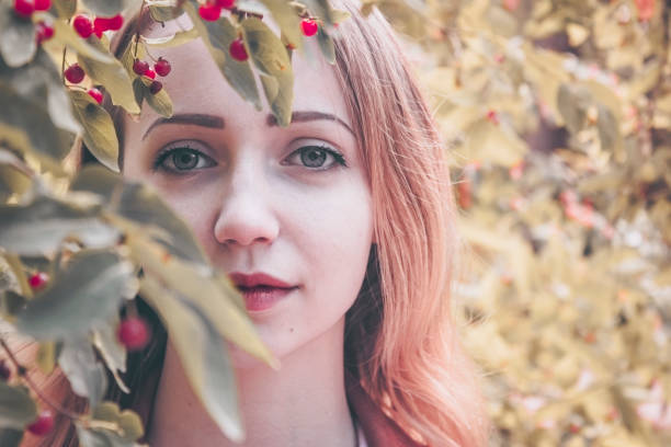 the girl is slightly hiding behind a Bush with ripe berries of viburnum