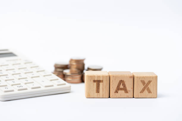 Word block "TAX", calculator, and pile of coins. Income, expenses, tax, financial data. stock photo