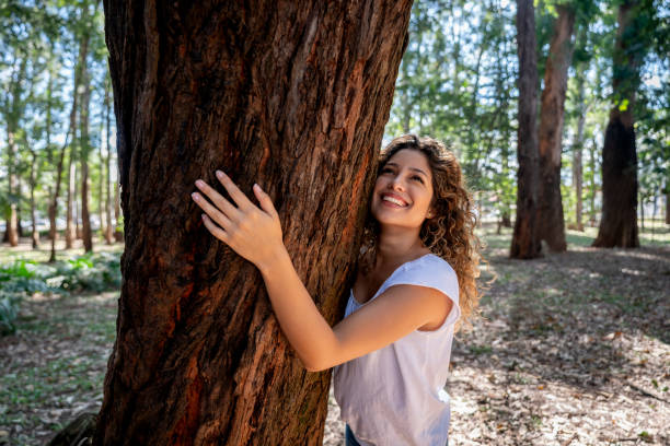 mulher feliz que abraça uma árvore no parque - abraçar árvore - fotografias e filmes do acervo