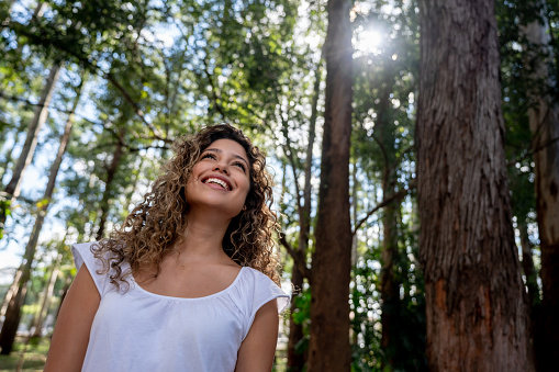 Portrait of a happy young woman walking in the forest and smiling