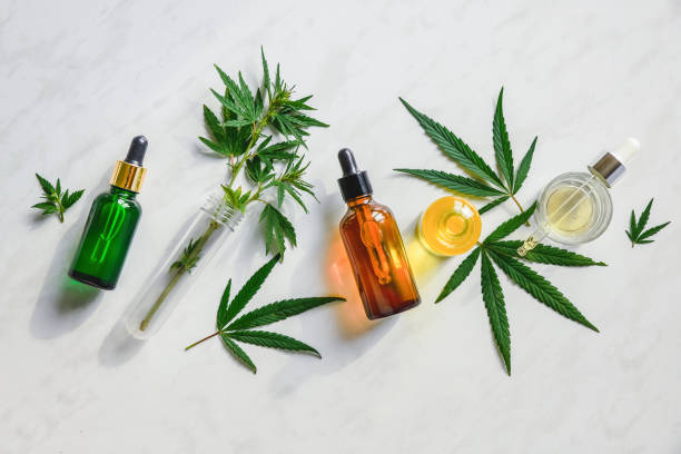 Various glass bottles with CBD oil, THC tincture and hemp leaves on a marble background. Flat lay, minimalism. Cosmetics CBD oil. Different glass bottles with CBD OIL, THC tincture and cannabis leaves on yellow background. Flat lay, minimalism. Cosmetics CBD oil. cbd oil photos stock pictures, royalty-free photos & images