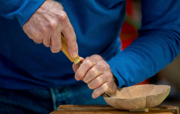 istock Older male woodwork craftsman's hands work on a wood sculpture with chisel. 1170030875