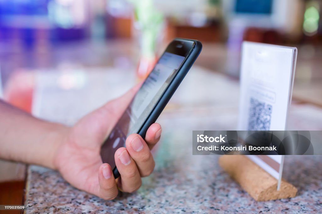 Closeup of a hand holding phone and scanning qr code. Man hand paying with qr code. Closeup of a hand holding phone and scanning qr code. Man hand paying with qr code. Customer hand making payment through smart phone and scan code. Selective focus QR Code Stock Photo