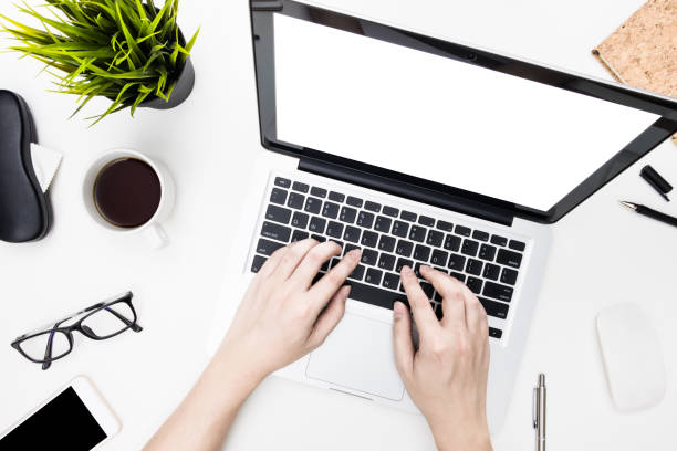 istock Blank laptop computer screen desktop with hands typing on keyboard over white office desk table with supplies. Top view, flat lay. 1170033307