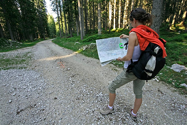 A woman figuring out where to go on her map in the woods young woman holding a map and compass, trying to figure out which way to go orienteering stock pictures, royalty-free photos & images