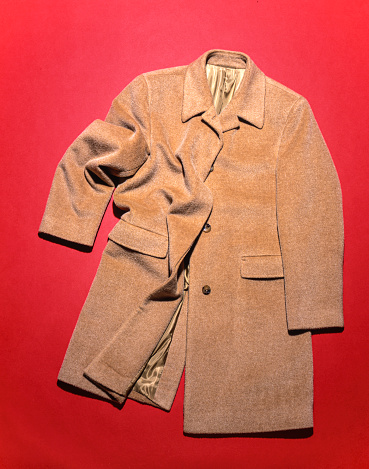 Men's coat on red backdrop, high angle studio shot. camel hair coat