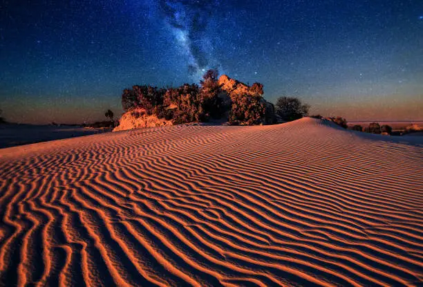 Sand dunes rippled by the wind under the starry night sky
