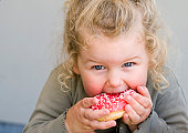 Little girl eating jelly-glazed donut with sprinkles