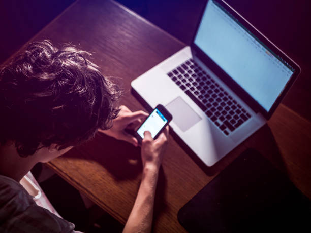 młody nastolatek przewijając mobilny smartfon w ciemnej sypialni późno w nocy - addiction internet computer working late zdjęcia i obrazy z banku zdjęć