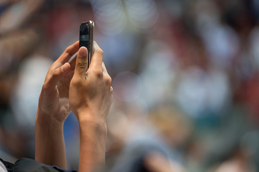 Close-up of unrecognizable person photographing using smart phone at sport event, Nikon Z7