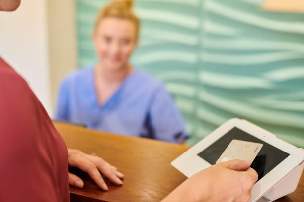 pagar el tratamiento - healthcare and medicine receptionist paying credit card fotografías e imágenes de stock