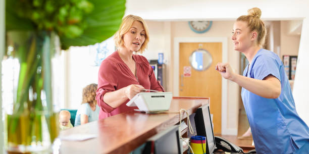 pagar el tratamiento - healthcare and medicine receptionist paying credit card fotografías e imágenes de stock