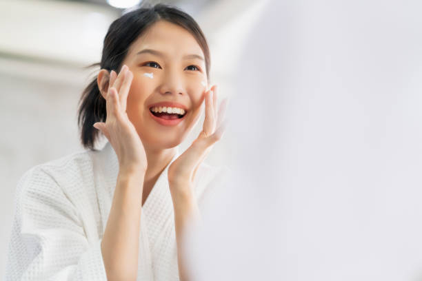 atractiva frescura asiática mujer limpia cara agua dulce con cuidado mirar a espejo en el fondo de la casa baño - human face water washing women fotografías e imágenes de stock