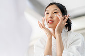 attractive freshness asian woman clean face fresh water with care look to mirror in bathroom home background