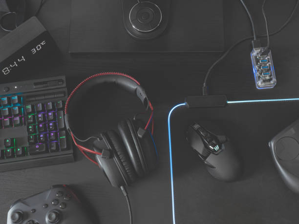 gamer work space concept, top view a gaming gear, mouse, keyboard, joystick, headset, mobile joystick, in ear headphone and mouse pad on black table background. stock photo