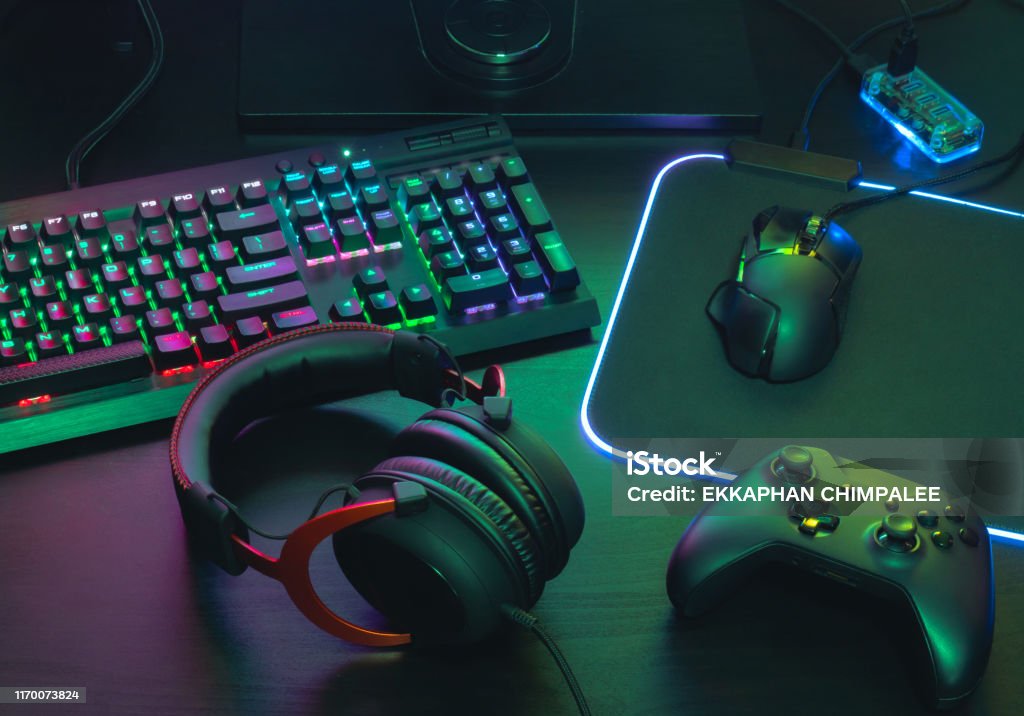 gamer work space concept, top view a gaming gear, mouse, keyboard, joystick, headset, mobile joystick, in ear headphone and mouse pad on black table background. Video Game Stock Photo
