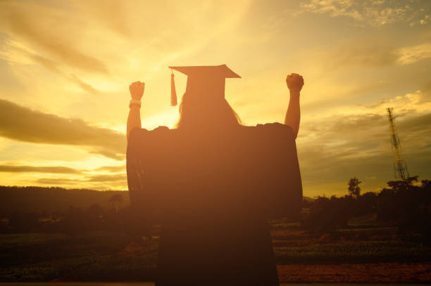 istock Sillhouette Graduation Female Stand for joy at sunset 1170078952