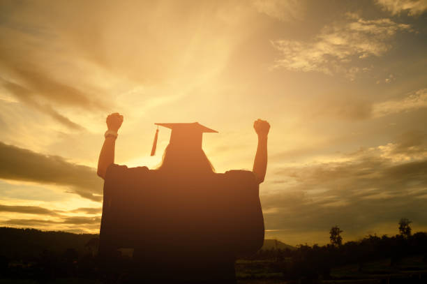 istock Sillhouette Graduation Female Stand for joy at sunset 1170079006