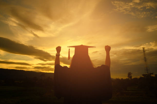 istock Sillhouette Graduation Female Stand for joy at sunset 1170079648