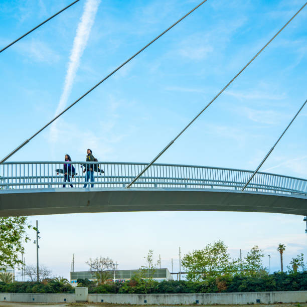 Two skaters with their longboards walking on an elevated walkway stock photo