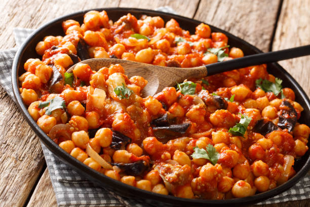 Spicy Middle Eastern chickpea food with eggplant, tomatoes, onions, herbs and spices closeup on a plate. horizontal Spicy Middle Eastern chickpea food with eggplant, tomatoes, onions, herbs and spices closeup on a plate on the table. horizontal chick pea stock pictures, royalty-free photos & images