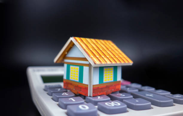 small houses and calculators in a black background - immovable imagens e fotografias de stock