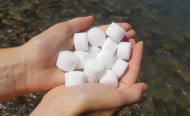 salzpellets für den wasserenthärter. salz in weiblichen händen - water softener stock-fotos und bilder