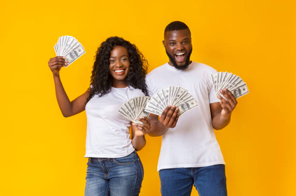 istock Afro couple is holding money on yellow studio background 1170086217