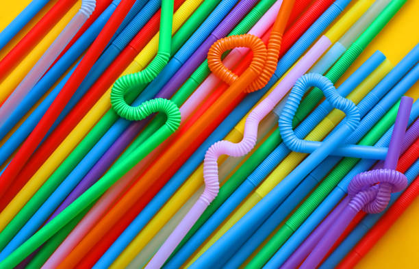 istock Colour plastic cocktail tubes with a flexible part, due to which they can be twisted into a knot or in a zigzag, or a heart shape, on a yellow background.  Eco concept 1170089140