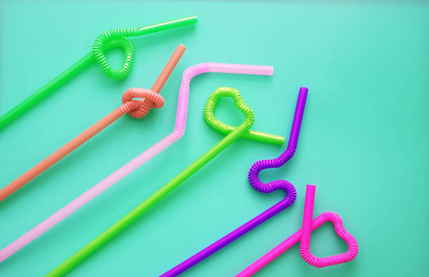 istock Colour plastic cocktail tubes with a flexible part, due to which they can be twisted into a knot or in a zigzag, or a heart shape, on a blue background. Modern and trendy colors. Eco concept 1170089293