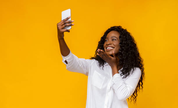 istock Cheerful black girl holding cellphone and making selfie 1170089297