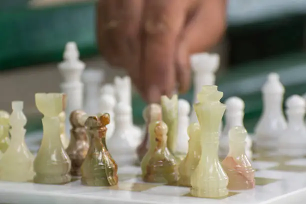 Chess game: grandmaster makes a move. Dedicated to International Chess Day.