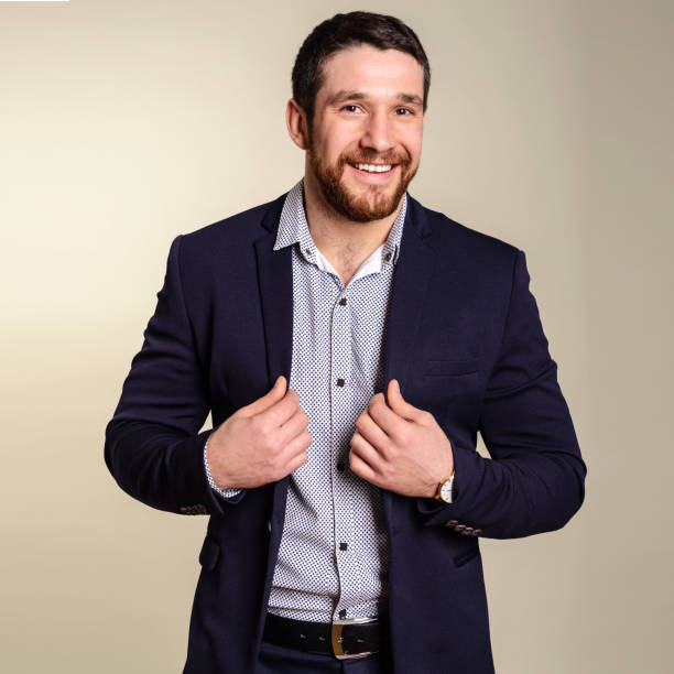 istock Cool and trendy. Handsome young bearded man adjusting his jacket standing against grey background 1170090962