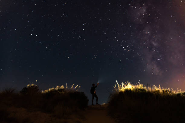 istock Man under night sky with stars on sand dunes. 1170095354